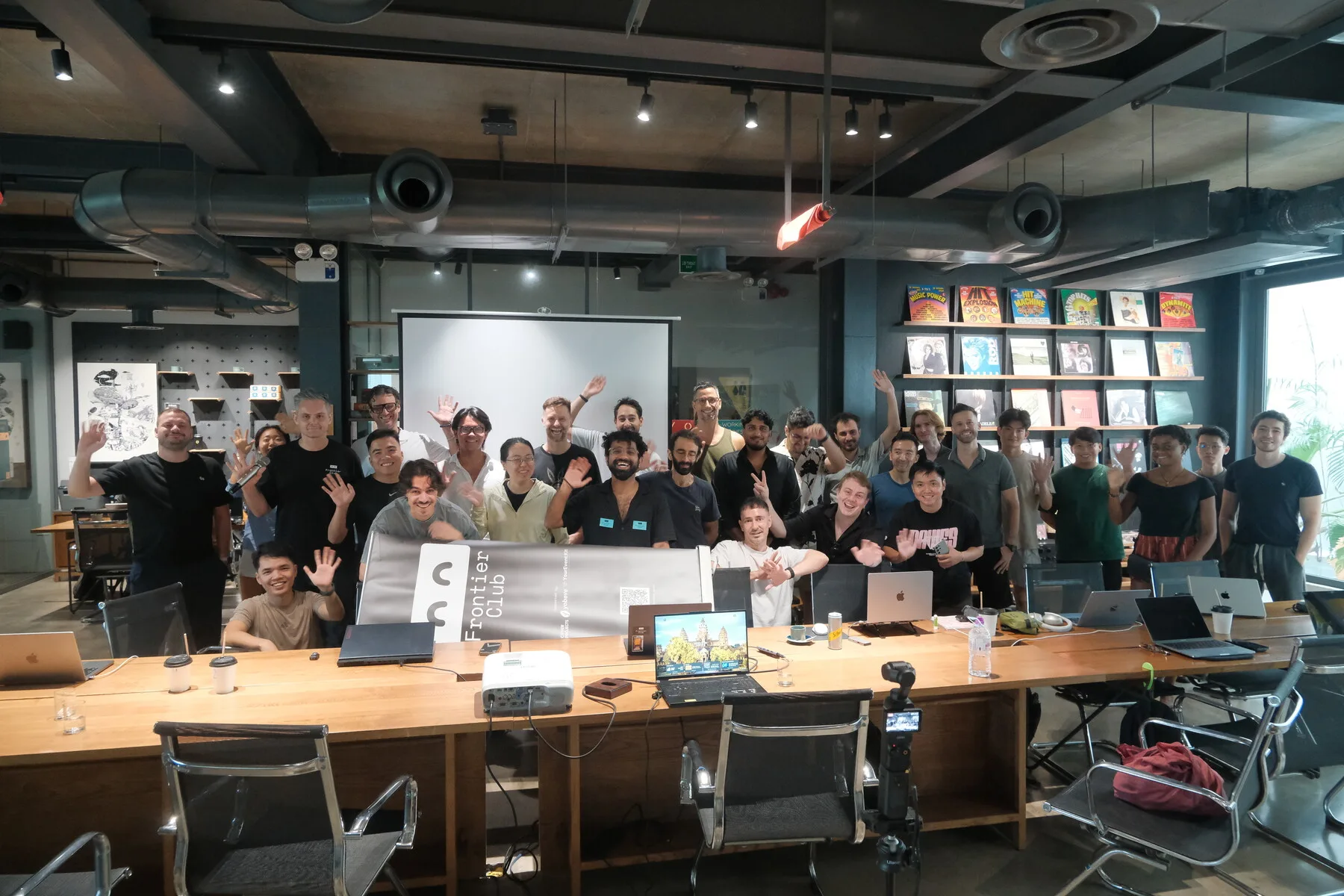 Builders waving behind the long table at Frontier Club AI Meetup #3